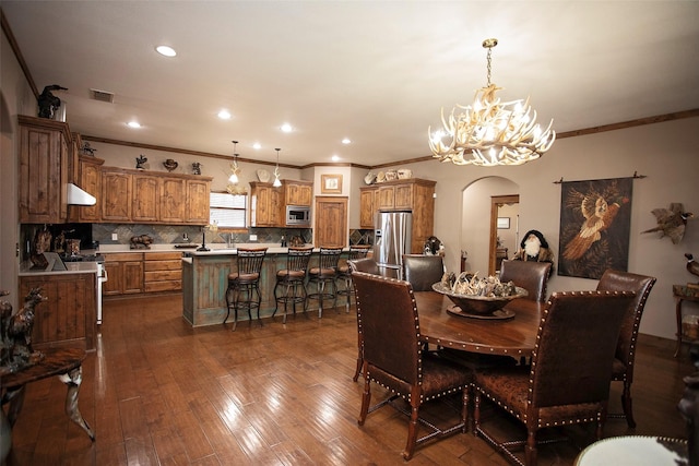 dining area with arched walkways, dark wood-style flooring, visible vents, and recessed lighting