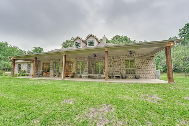 rear view of property featuring a yard, brick siding, a patio, and a ceiling fan