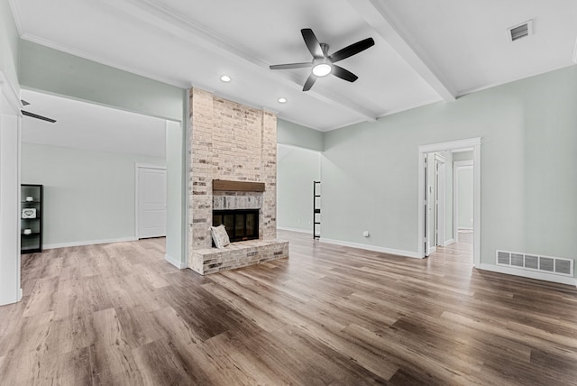 unfurnished living room featuring beam ceiling, a fireplace, wood finished floors, and visible vents