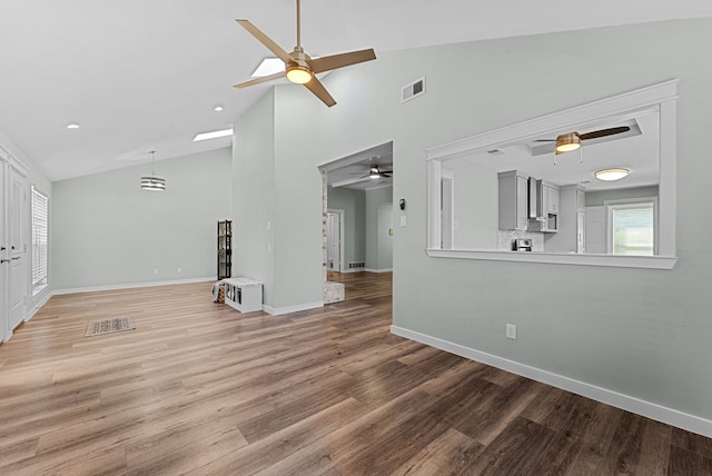 unfurnished living room featuring visible vents, a ceiling fan, high vaulted ceiling, light wood-type flooring, and baseboards