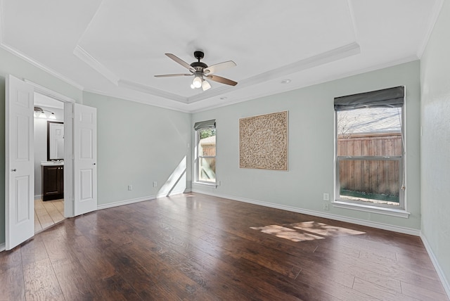 empty room with baseboards, a raised ceiling, ceiling fan, hardwood / wood-style floors, and crown molding