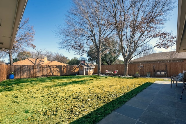 view of yard featuring a shed, a fenced backyard, a patio, and an outbuilding