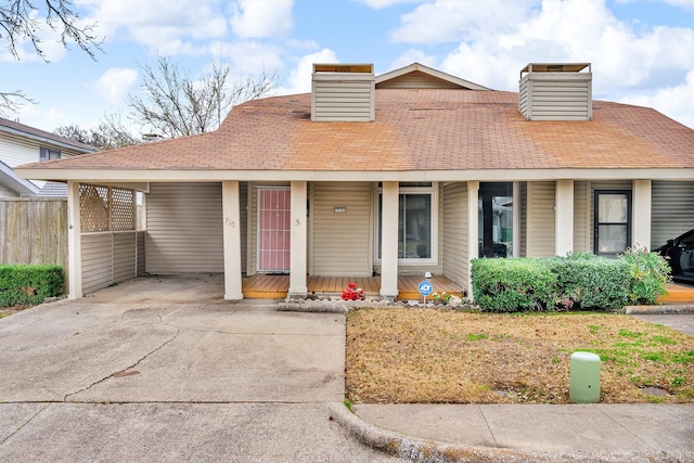 view of front of house with a carport, covered porch, a chimney, and concrete driveway