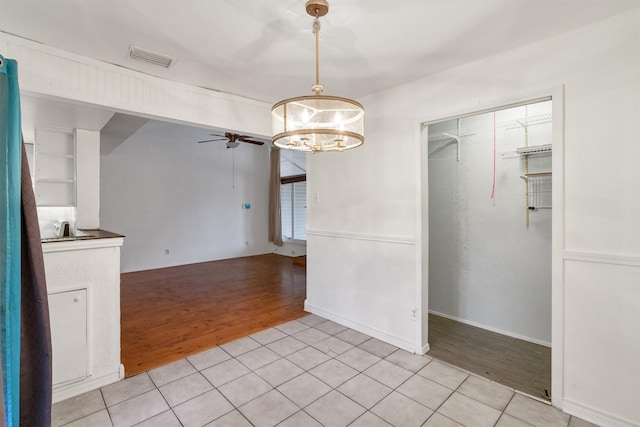 unfurnished dining area with visible vents, light wood finished floors, and ceiling fan with notable chandelier