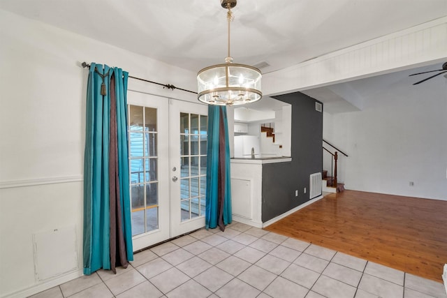 unfurnished dining area with visible vents, wood finished floors, an inviting chandelier, stairs, and french doors