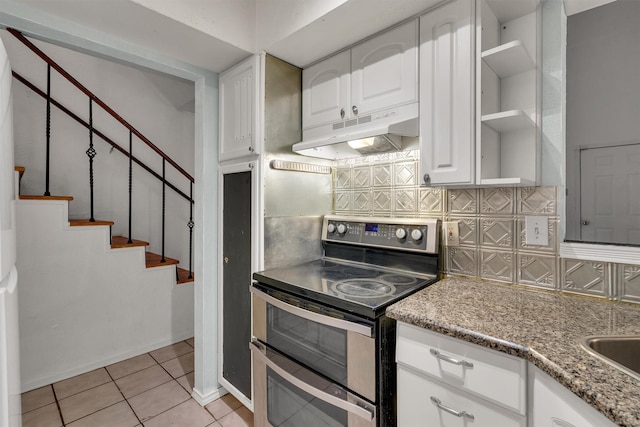 kitchen with range with two ovens, light tile patterned flooring, under cabinet range hood, open shelves, and tasteful backsplash