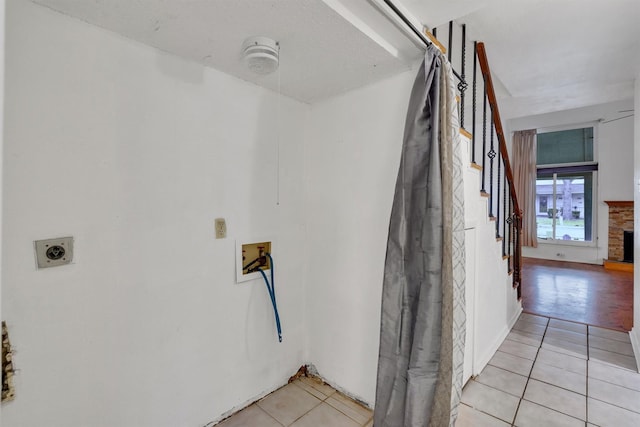 hall featuring light tile patterned floors, stairway, and baseboards