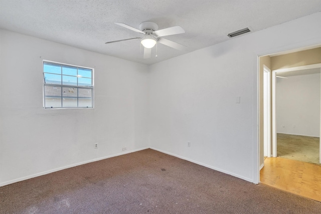 unfurnished room featuring a textured ceiling, ceiling fan, carpet flooring, visible vents, and baseboards