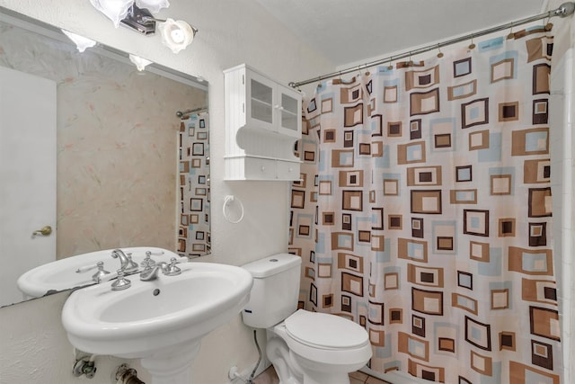 bathroom with toilet, a shower with curtain, a sink, and a textured wall