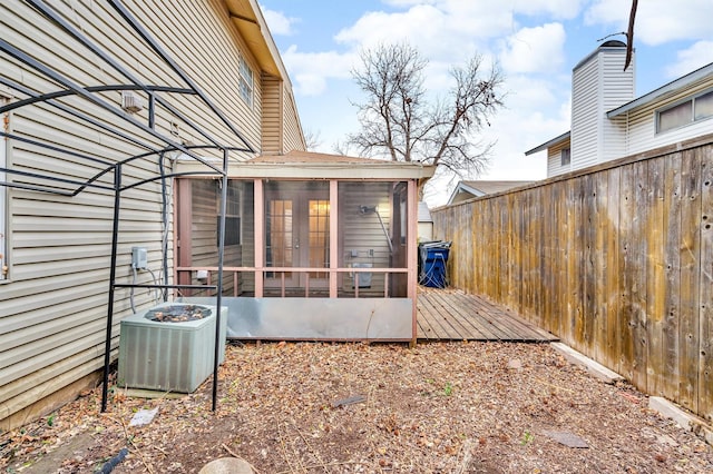 rear view of property with a sunroom, central AC, and fence