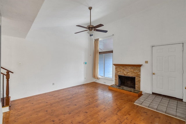 unfurnished living room with a ceiling fan, vaulted ceiling, a fireplace, and wood finished floors