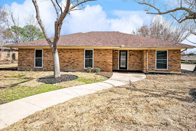 single story home featuring a shingled roof and brick siding