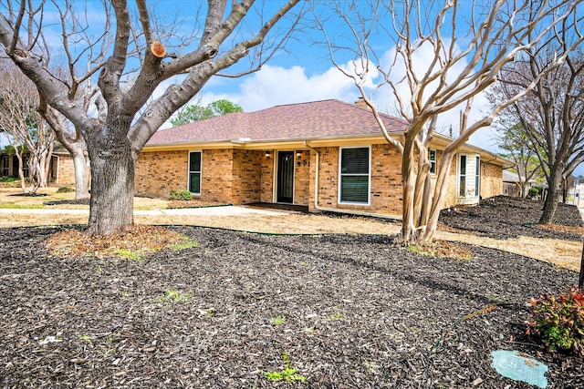 ranch-style house with a patio, brick siding, and a shingled roof