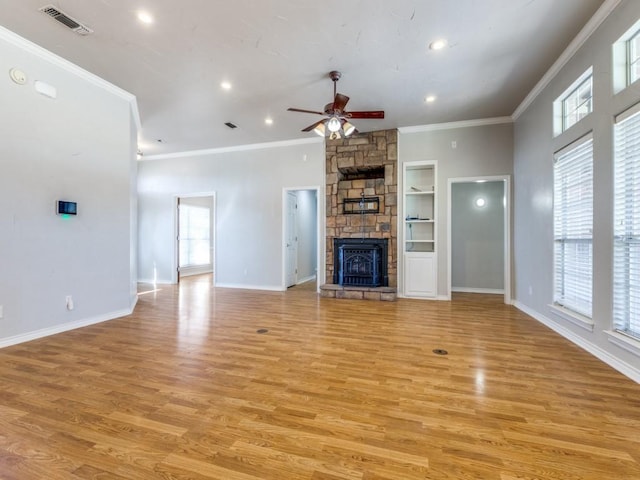 unfurnished living room featuring crown molding, visible vents, light wood-style flooring, a stone fireplace, and baseboards