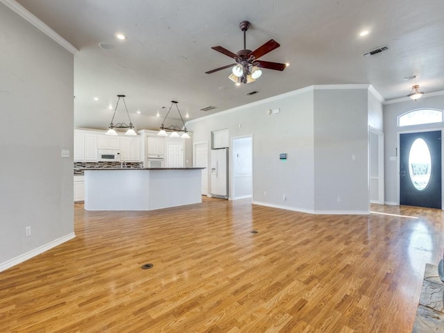 unfurnished living room featuring baseboards, light wood-style flooring, visible vents, and crown molding