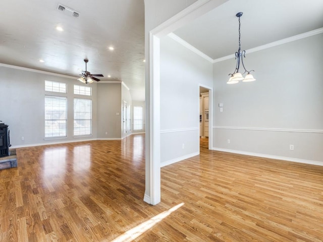 unfurnished living room featuring a wood stove, light wood-style floors, baseboards, and ceiling fan with notable chandelier