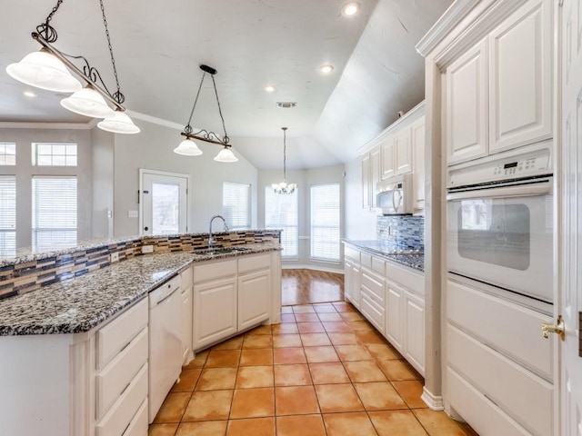 kitchen featuring white appliances, white cabinets, decorative backsplash, lofted ceiling, and a sink