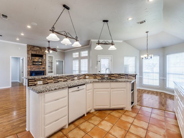 kitchen with a stone fireplace, white dishwasher, a sink, visible vents, and open floor plan