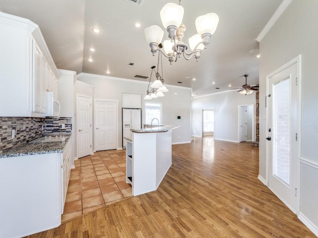 kitchen with white appliances, a sink, white cabinets, decorative backsplash, and crown molding