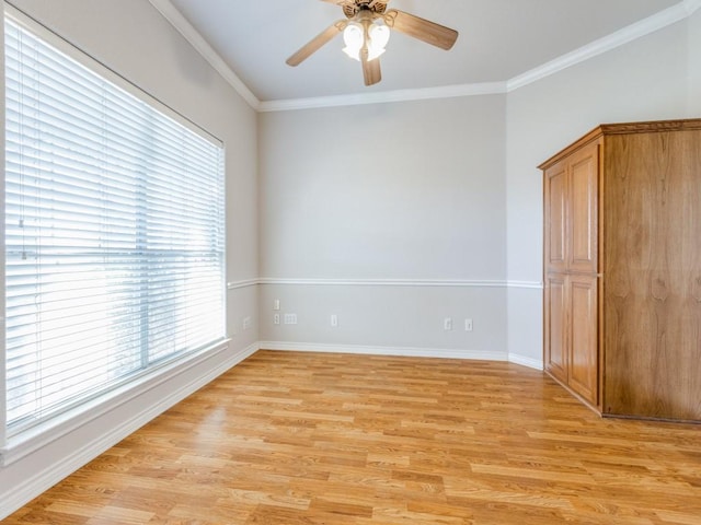 spare room featuring light wood finished floors, baseboards, a ceiling fan, and crown molding