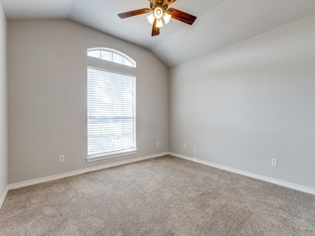 carpeted empty room featuring baseboards, vaulted ceiling, and a ceiling fan