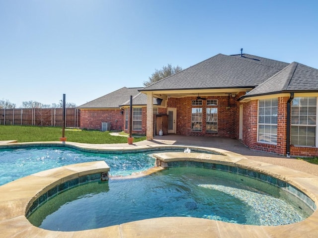 view of pool with ceiling fan, central AC unit, fence, a pool with connected hot tub, and a patio area