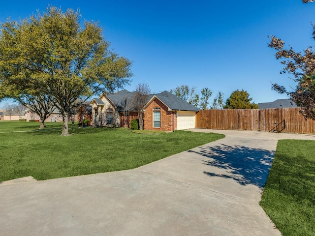 view of front facade with a garage, brick siding, fence, driveway, and a front yard