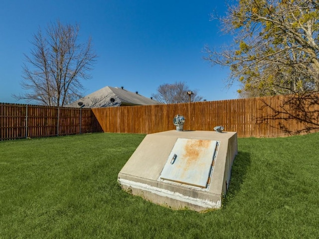 view of storm shelter with a fenced backyard and a lawn