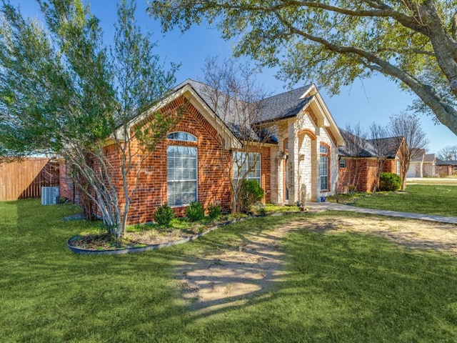 view of front of home with stone siding, fence, a front lawn, central AC, and brick siding