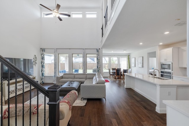 living area featuring dark wood-style floors, recessed lighting, stairway, a towering ceiling, and baseboards