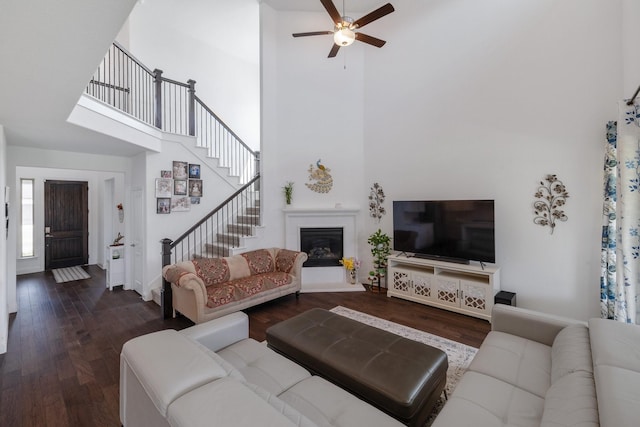 living area with a towering ceiling, stairway, and dark wood-style flooring