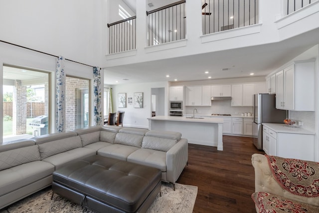 living room with a high ceiling, baseboards, dark wood-style flooring, and recessed lighting