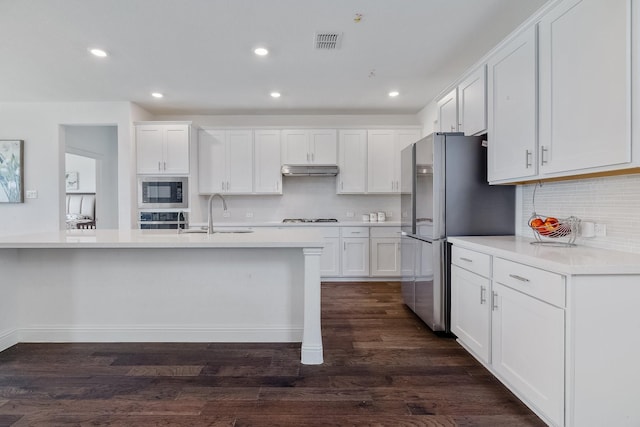 kitchen featuring visible vents, white cabinets, stainless steel appliances, under cabinet range hood, and a sink