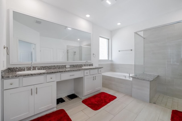 bathroom featuring double vanity, a garden tub, a shower stall, and a sink