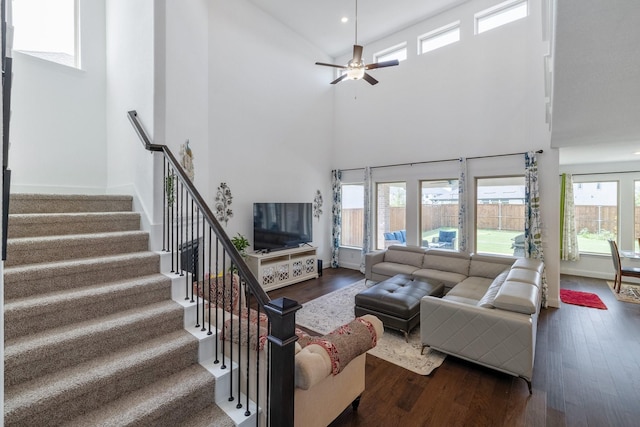 living area with stairway, a high ceiling, and wood finished floors