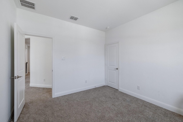 empty room with baseboards, visible vents, and carpet flooring