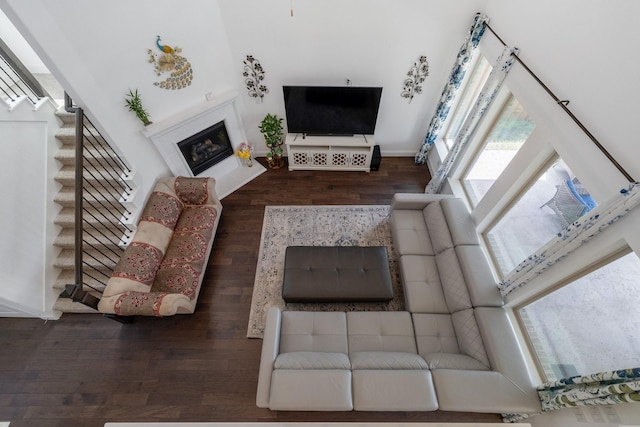 living area with stairway, wood finished floors, and a glass covered fireplace