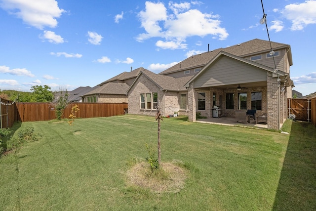 rear view of property featuring a lawn, a patio, a fenced backyard, ceiling fan, and brick siding