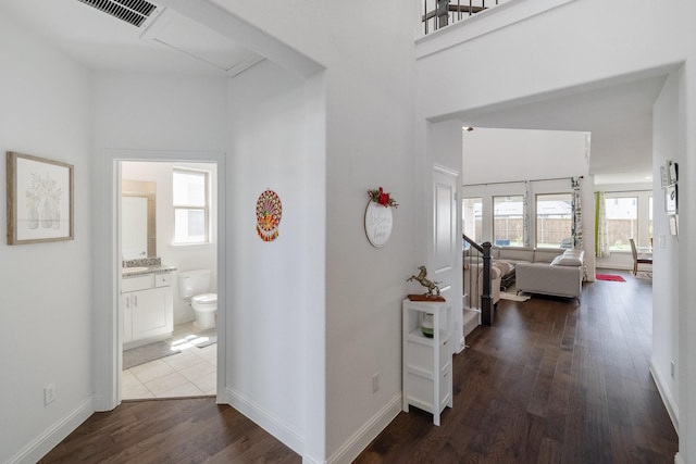 corridor with baseboards, visible vents, dark wood finished floors, and a sink