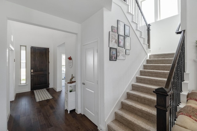 foyer entrance featuring stairs, baseboards, and dark wood finished floors