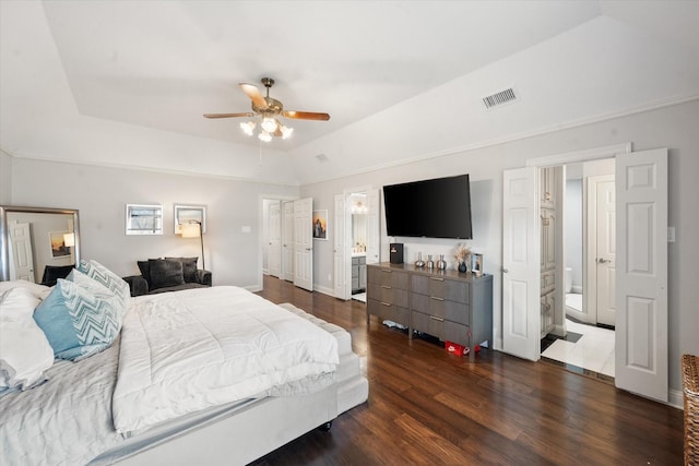 bedroom with dark wood-style flooring, visible vents, a ceiling fan, a tray ceiling, and ensuite bath