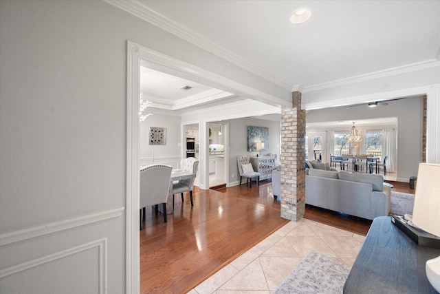 living room featuring light tile patterned floors, ornamental molding, a chandelier, and decorative columns