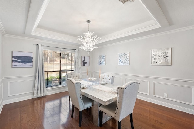 dining space featuring visible vents, dark wood finished floors, ornamental molding, a raised ceiling, and an inviting chandelier