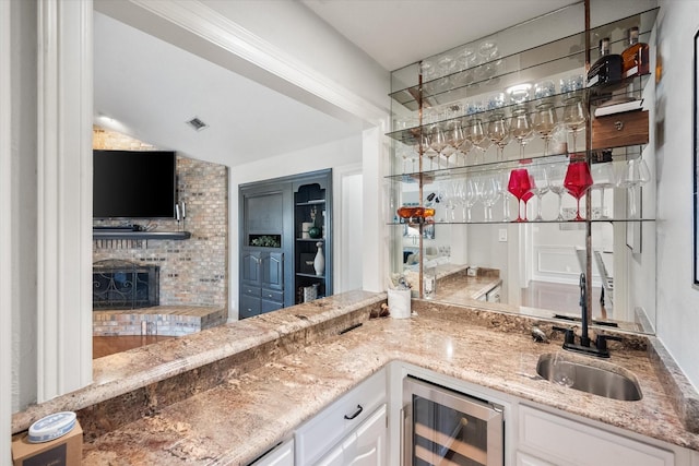 bar with beverage cooler, a fireplace, indoor wet bar, and a sink