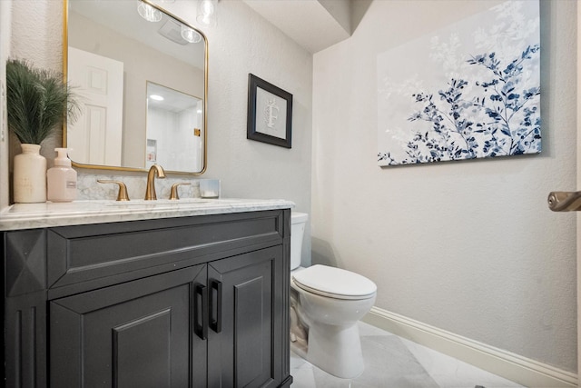 half bathroom with baseboards, vanity, and toilet