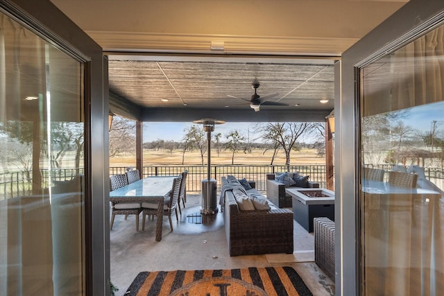 view of patio featuring a ceiling fan and an outdoor living space with a fire pit