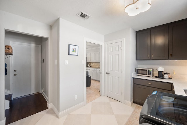 kitchen featuring visible vents, range, baseboards, stainless steel microwave, and light countertops