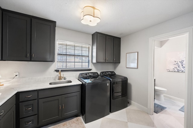 laundry room with cabinet space, baseboards, washer and clothes dryer, and a sink