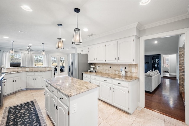 kitchen with light tile patterned floors, visible vents, stainless steel fridge with ice dispenser, a kitchen island, and white cabinetry