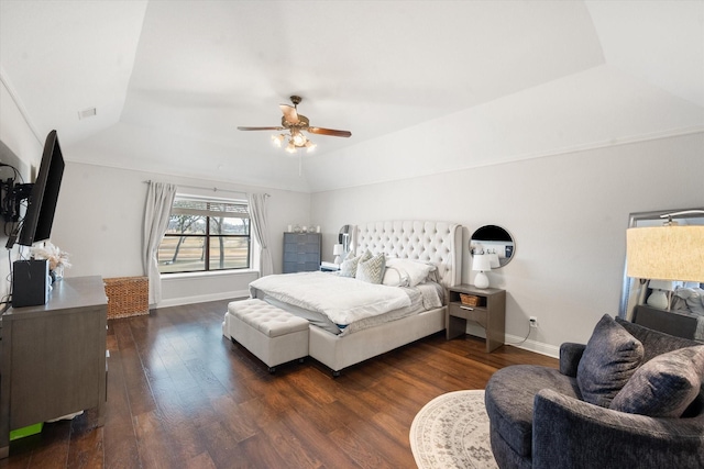 bedroom featuring lofted ceiling, dark wood-style floors, baseboards, and a tray ceiling